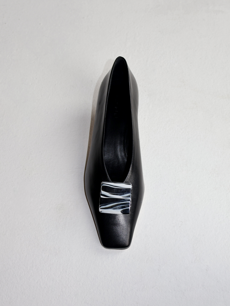 Black square shoe clip with paint-like white stripes on black heel