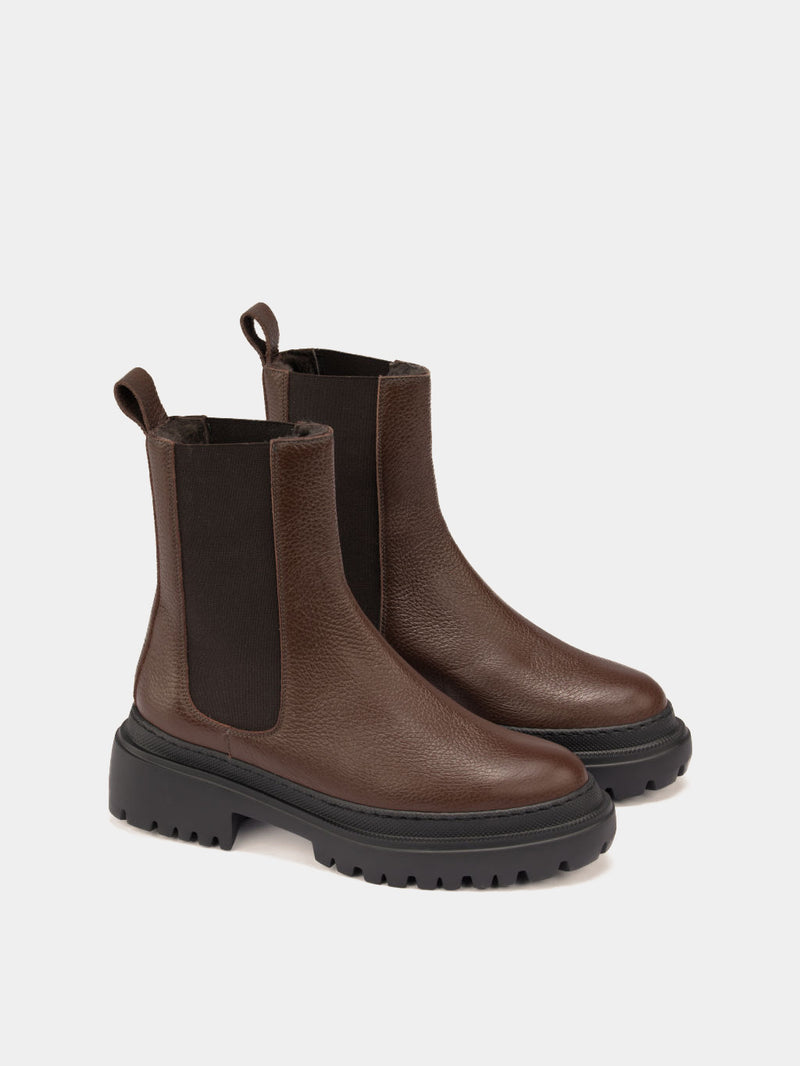 Pair of brown Chelsea boots on a light gray background