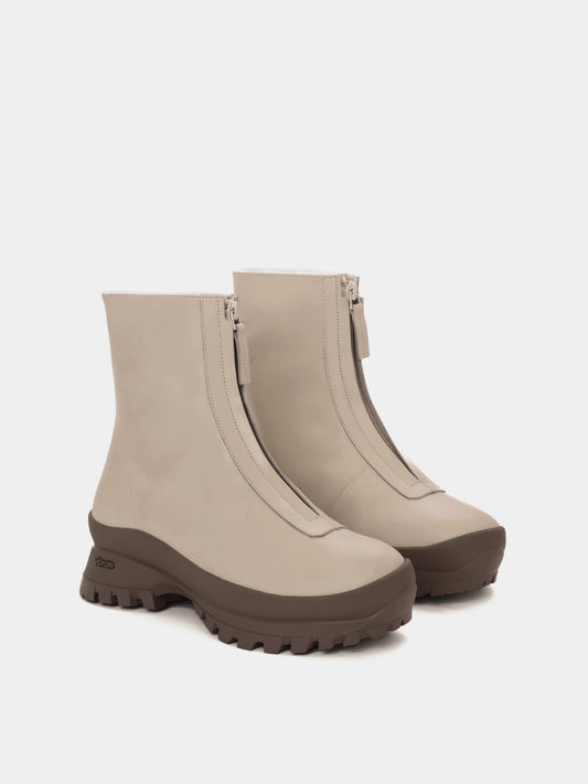 Cream fur-lined boots with a zipper going down the middle and taupe vibram soles
