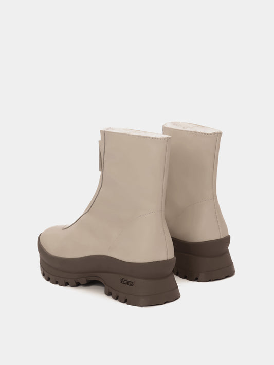Cream fur-lined boots with a zipper going down the middle and taupe vibram soles