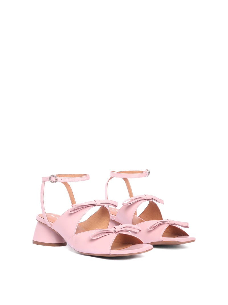 Blush leather heels with two straps adorned with bows and an ankle strap