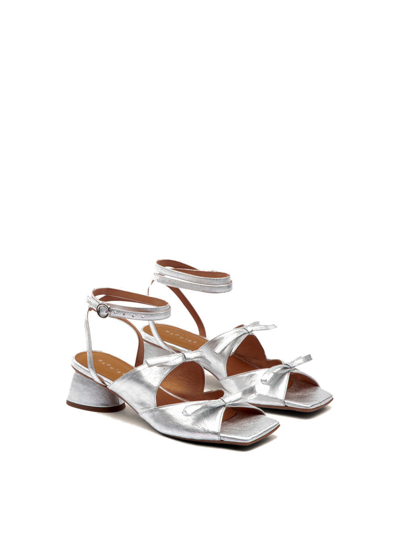 Silver healed sandal with ankle strap, open toe and two bows.