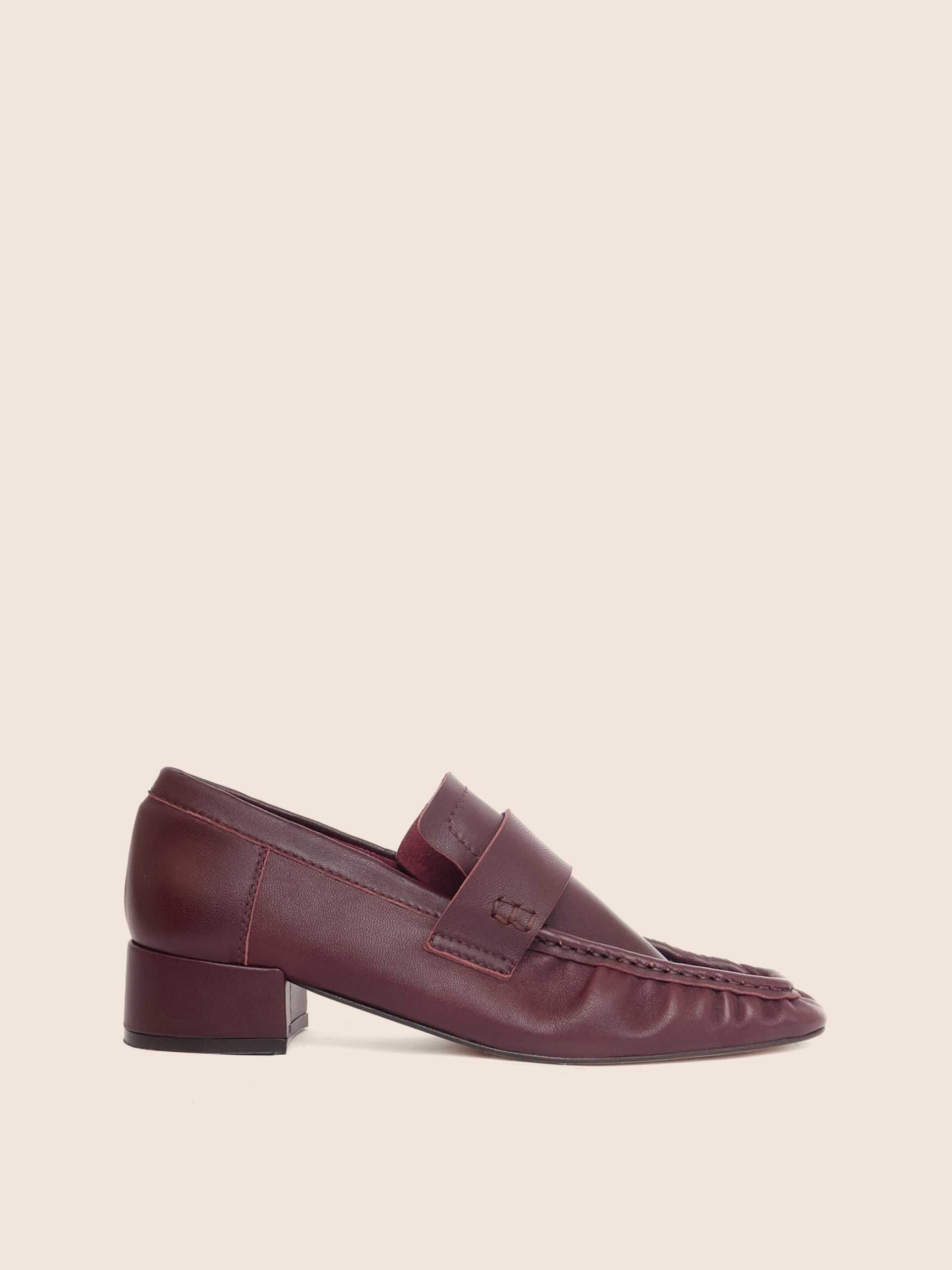 Bordeaux loafer shoe on a beige background