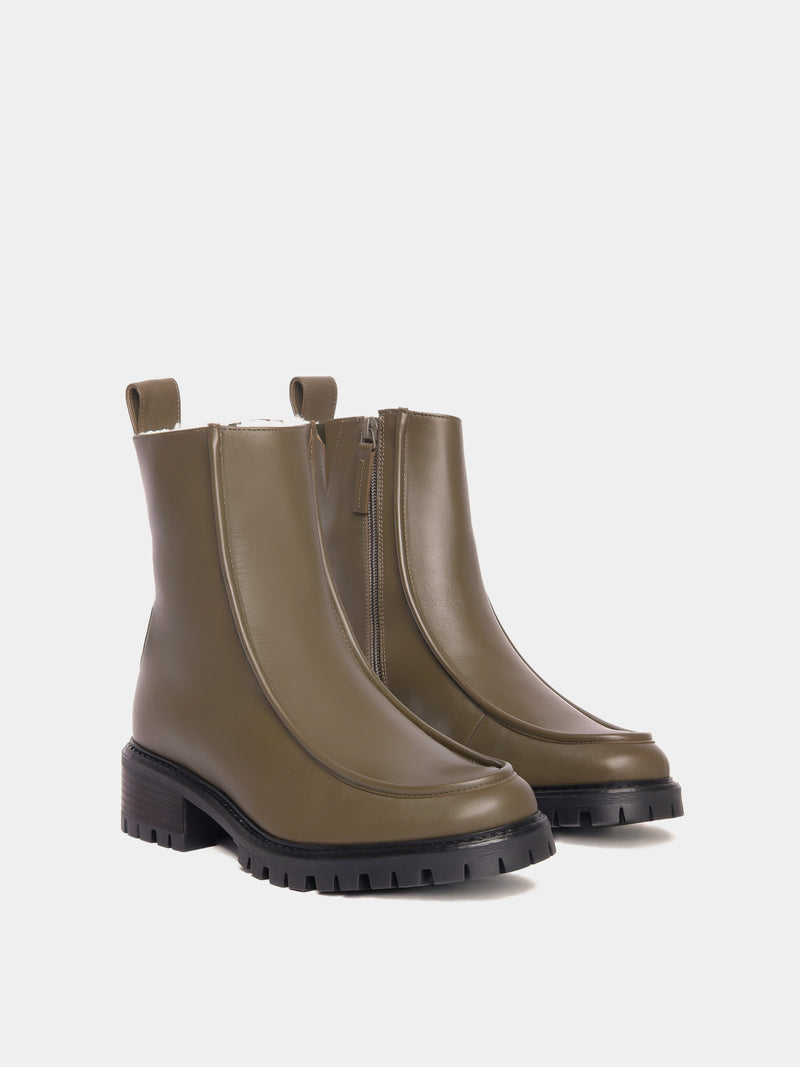 Shearling lined winter boot with a front piping detail, in an olive green leather with a black lug outsole. 
