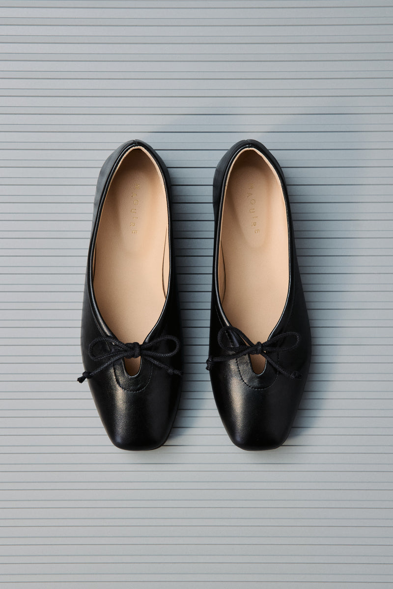 Pair of black shoes with bows on a textured gray background