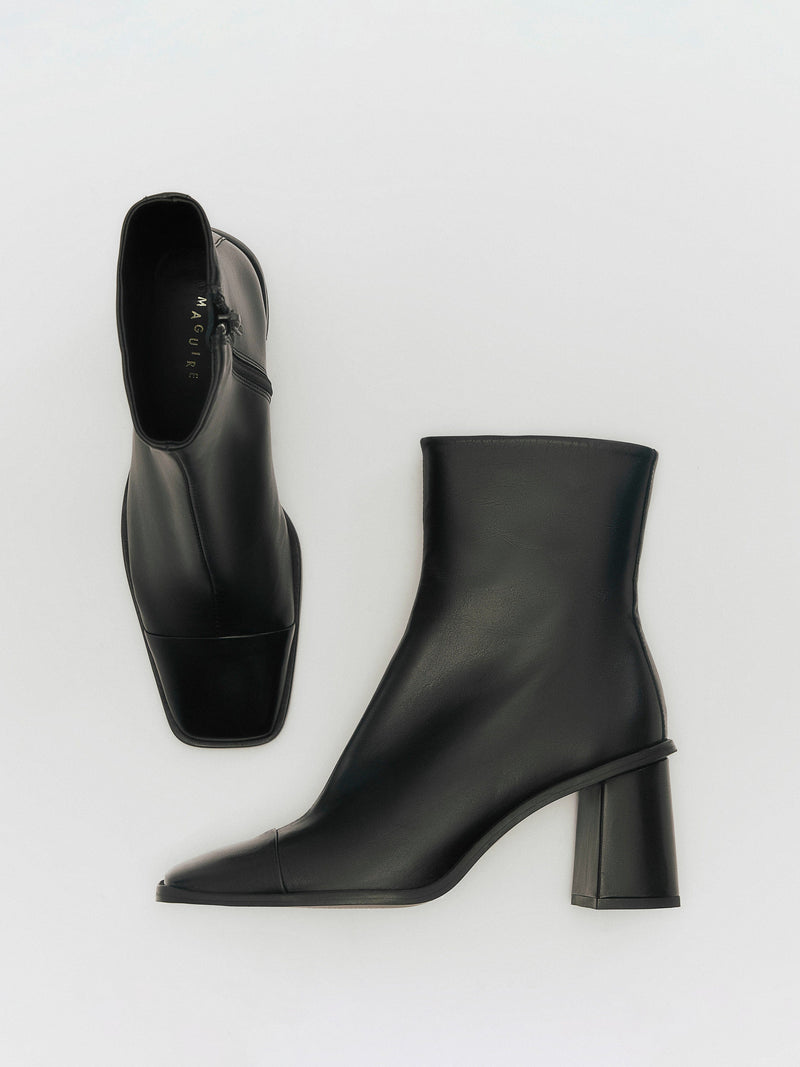 A black heeled boot with a square toe on a white background