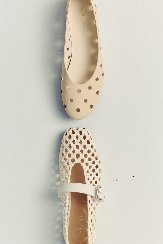 two ballet flats on white floor facing each oter. both leather and cream coloured with perforated details