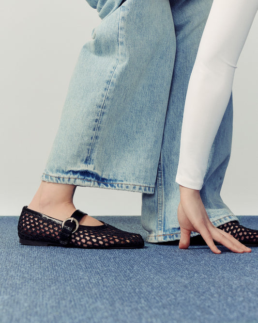 woman bending down wearing white shirt and blue jeans over blue carpet