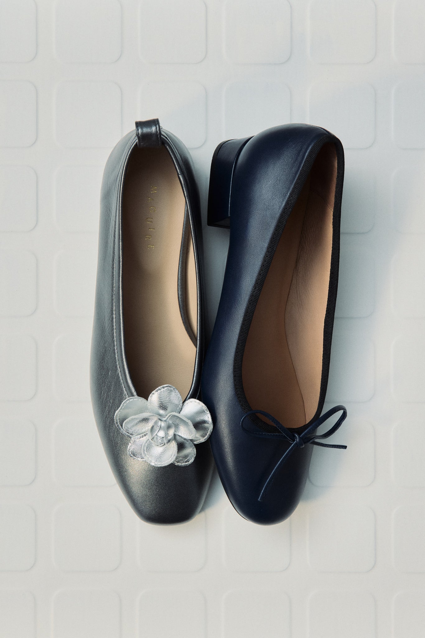 Pair of black shoes with a decorative flower on a textured white surface