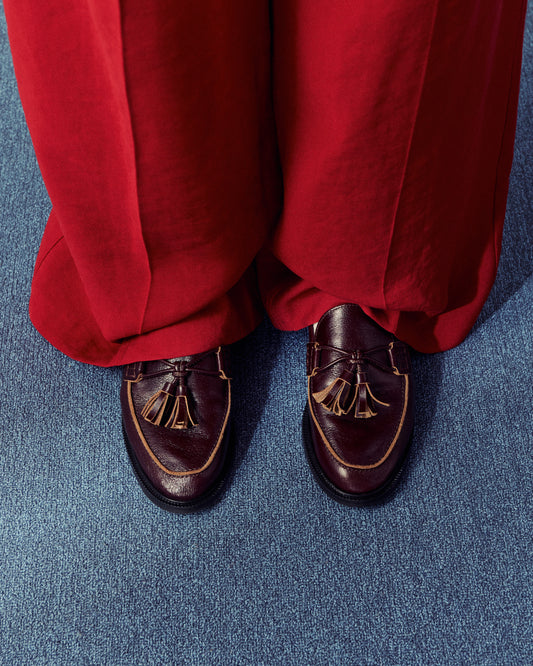 woman wearing bright red pants and brown loafers standing on blue carpet