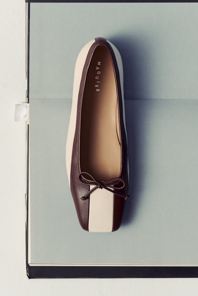 brown and white striped ballet flat with bow laying on open book