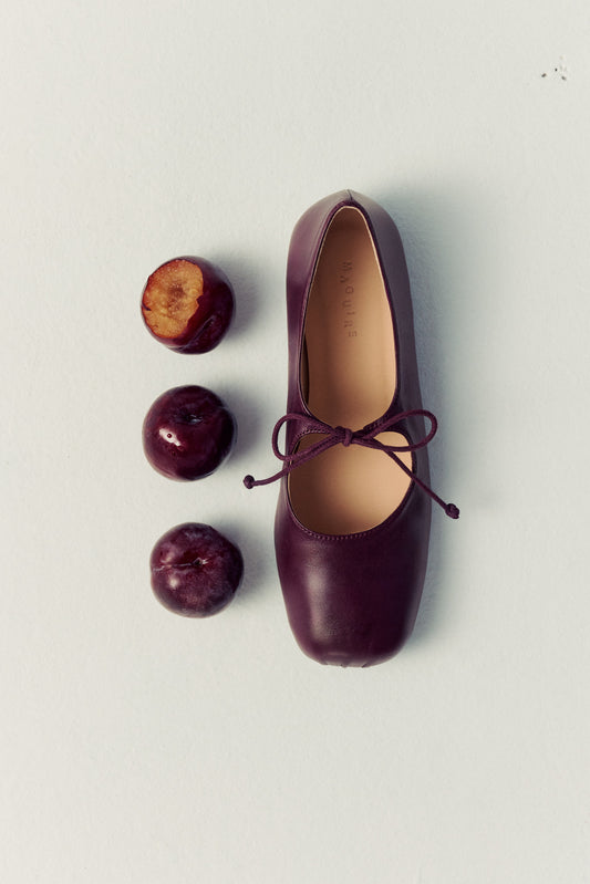 plum ballet flat with lace detailing and three plums next to it