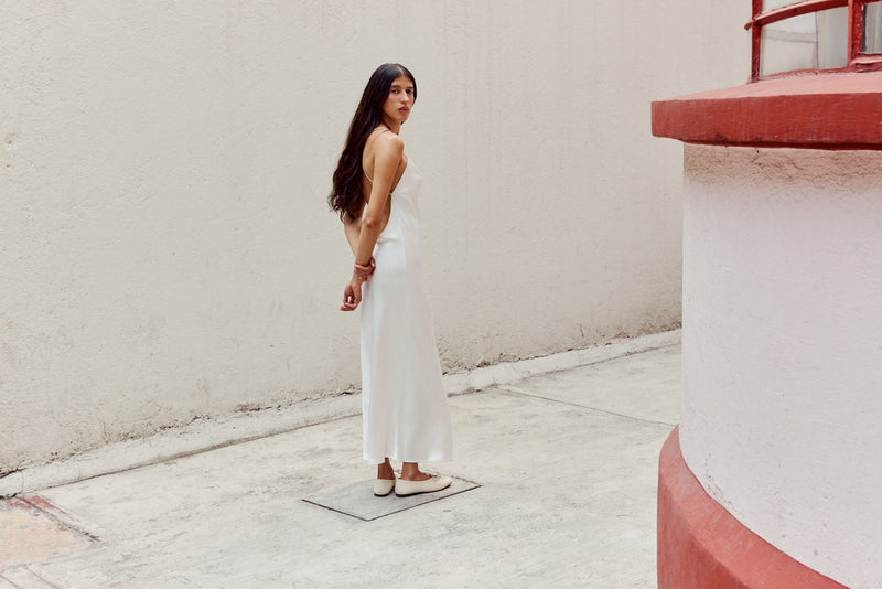 Woman in white dress wearing white ballerina flats on white background