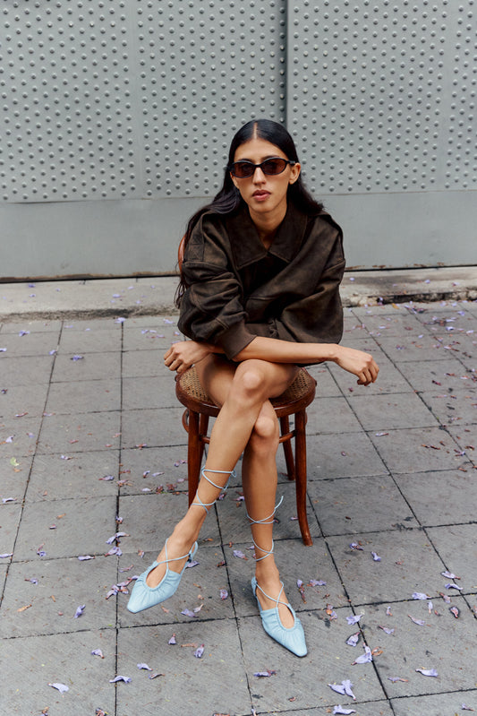 Woman sat on stool wearing blue strap heels on city street