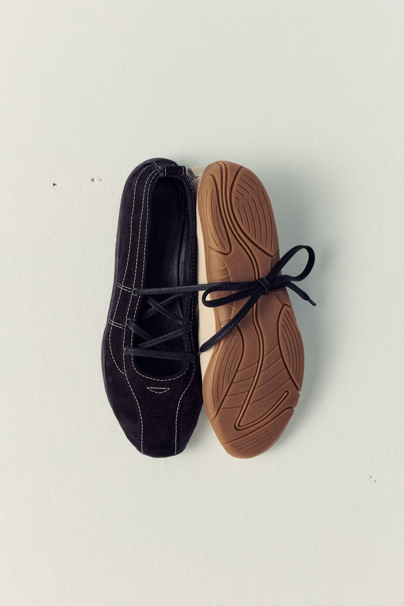 two ballet flats laying next to each other slightly one on top of the other, one's lace tied around the other
