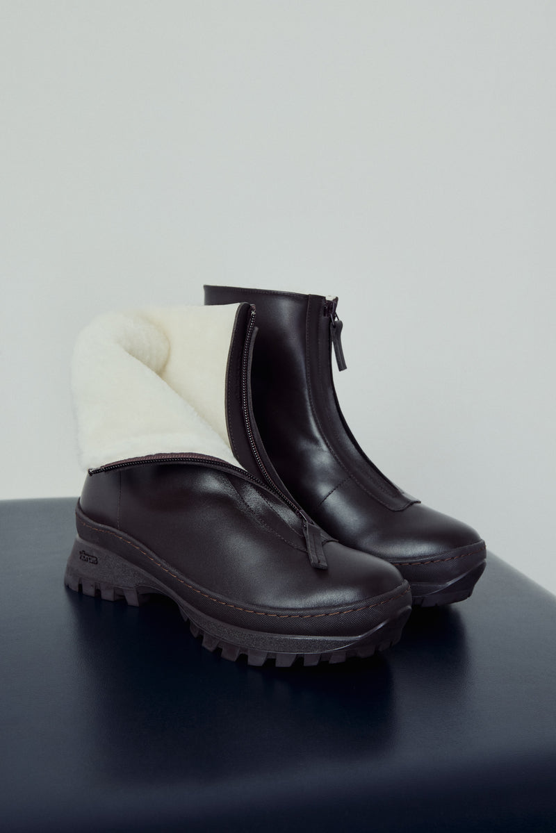 Pair of black boots with white lining on a dark surface and light gray background