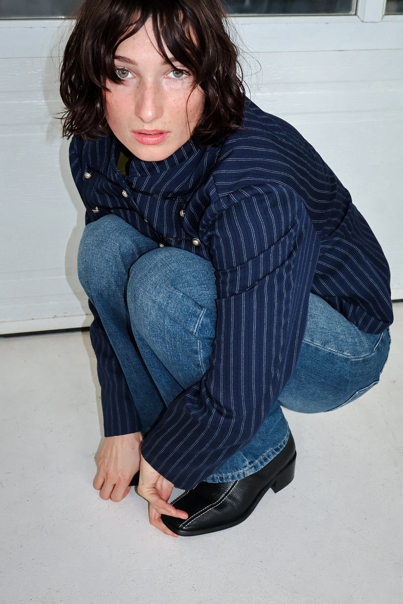 Beautiful model wearing blue outfit with black leather boots from Maguire Shoes, piercing blue eyes on the girl.