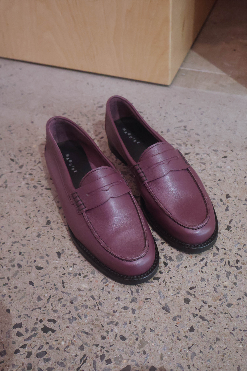 Pair of plum loafers on a speckled floor.